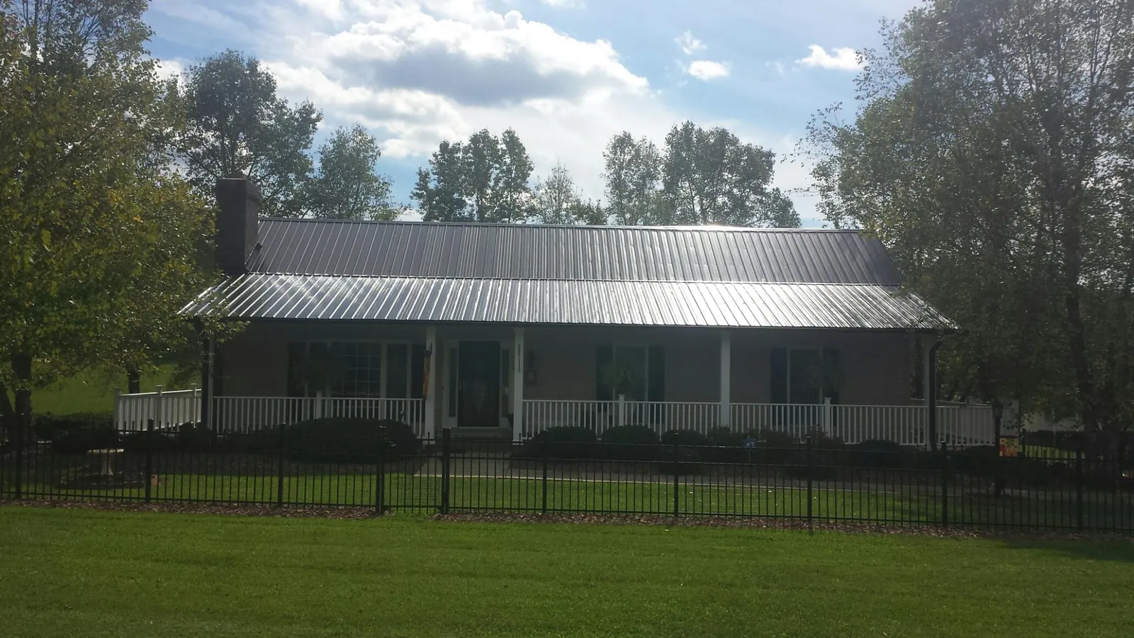 Gray metal roof on a brick ranch with a full width front porch — Gutter Guard Installation work by our crew in Delavan